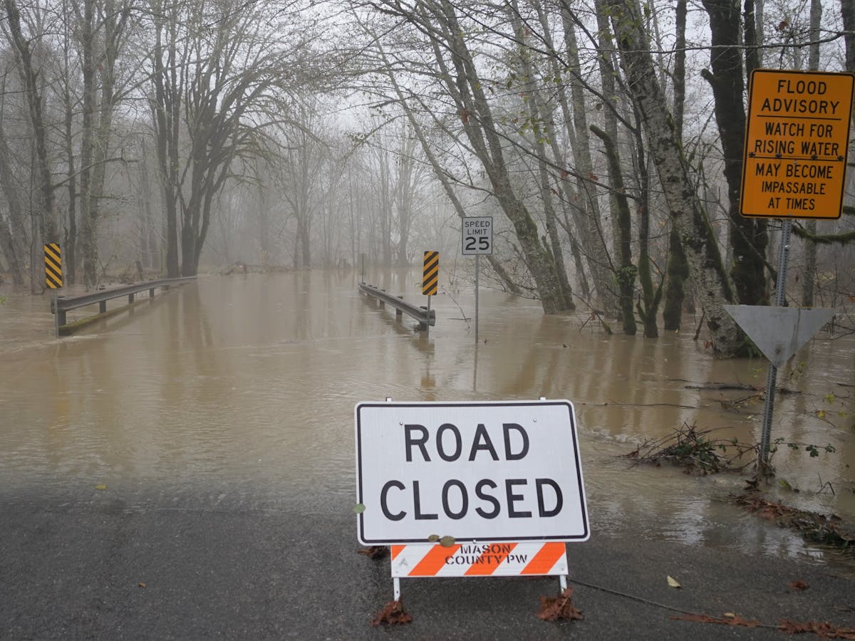road closed sign in front of a flooded street