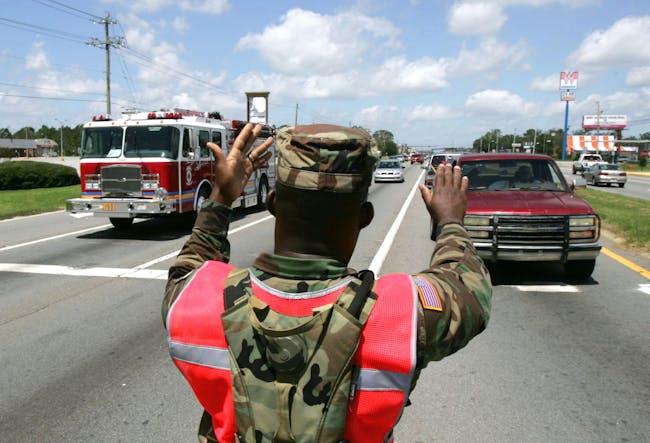 PENSACOLA, FL - JULY 11: US National Guardsman Sgt. Robert Gaines directs traffic July 11, 2005 in in Pensacola, Florida. He and other members of the 1st Battalion 265th ADA National Guard unit were activated to help with the recovery efforts from Hurricane Dennis. Traffic became congested as emergency vehicles and returning residents congested the cities roadways. (Photo by John Moore/Getty Images)