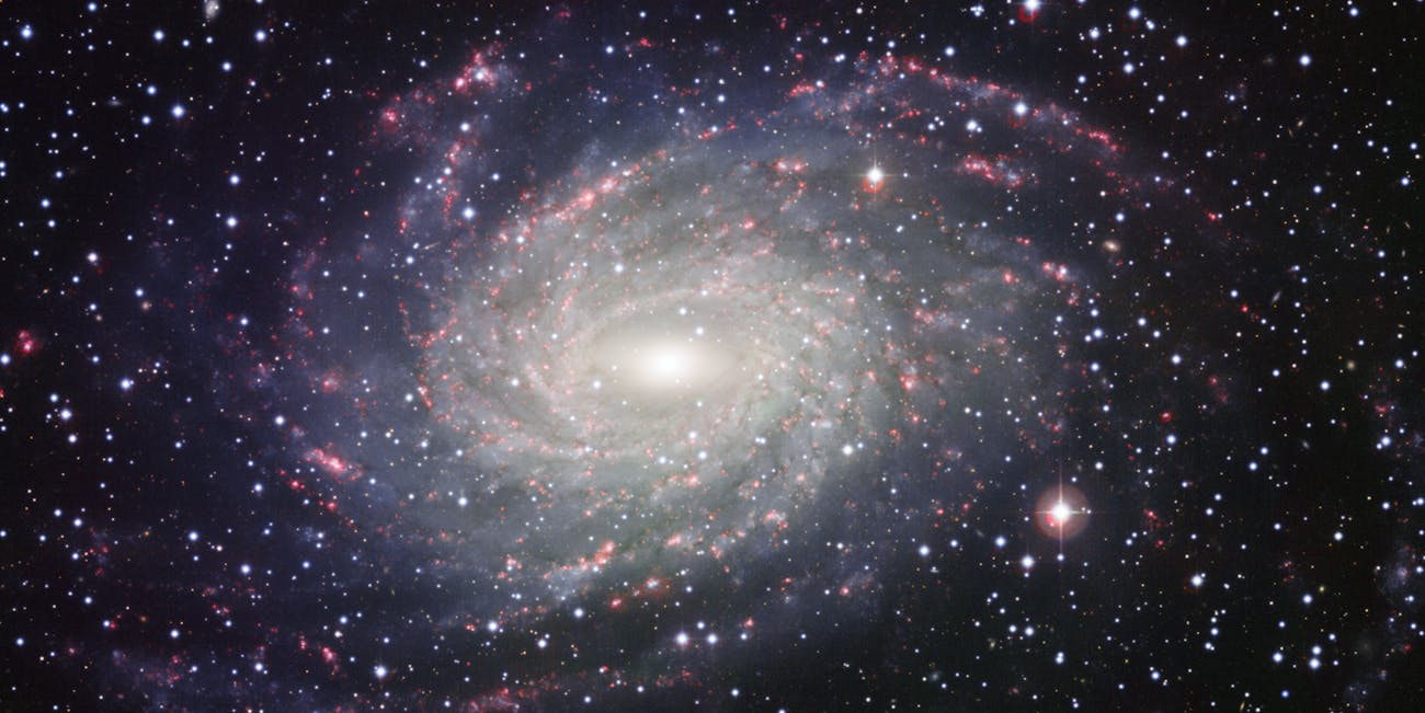 This picture of the nearby galaxy NGC 6744 was taken with the Wide Field Imager on the MPG/ESO 2.2-metre telescope at La Silla. The large spiral galaxy is similar to the Milky Way, making this image look like a picture postcard of our own galaxy sent from extragalactic space. The picture was created from exposures taken through four different filters that passed blue, yellow-green, red light, and the glow coming from hydrogen gas. These are shown in this picture as blue, green, orange and red, respectively.
