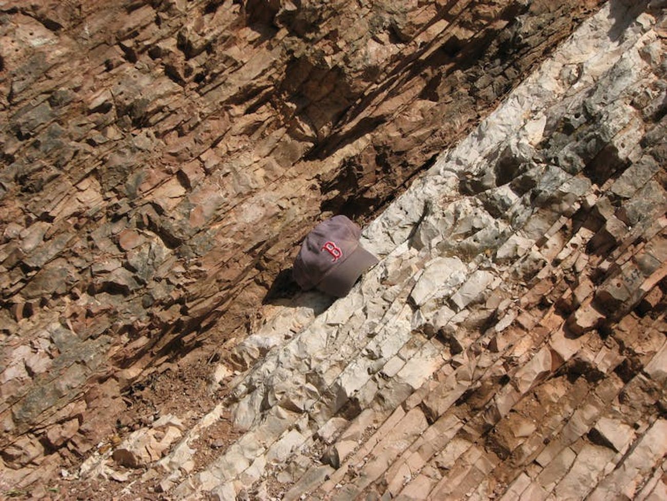   Rocks near Gubbio, Italy, change in color and texture on the line that indicates the Crypt-Paleogenic extinction event that wiped out the dinosaurs 66 million years ago. & # 39; A Baseball Hat Show Scale. 