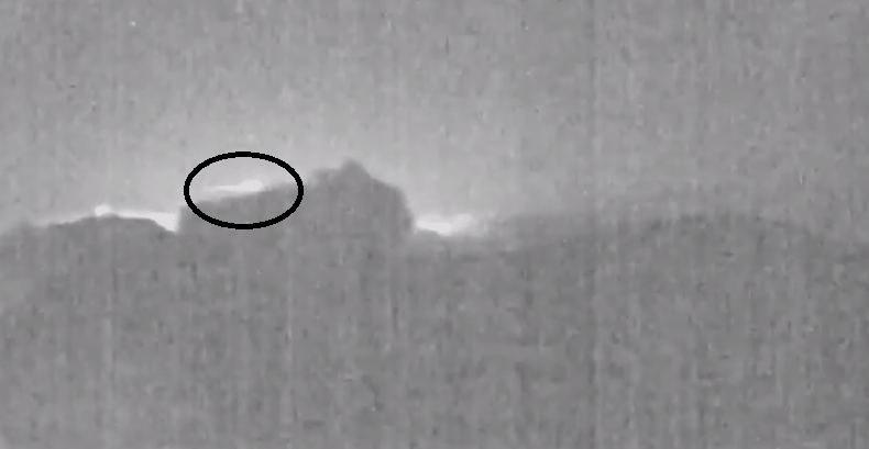 A meteor dashes behind an erupting volcano.