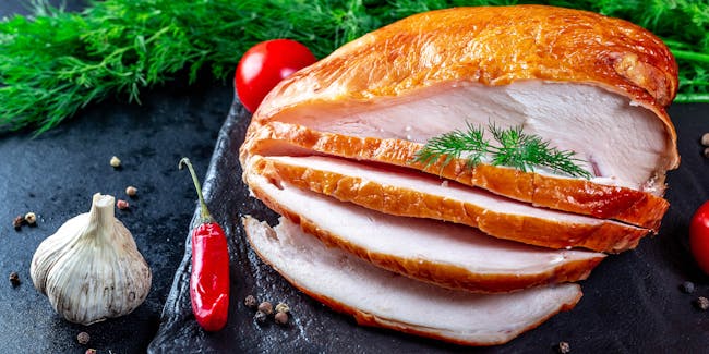 Delicious slicing of smoked chicken fillet with spices on a dark background