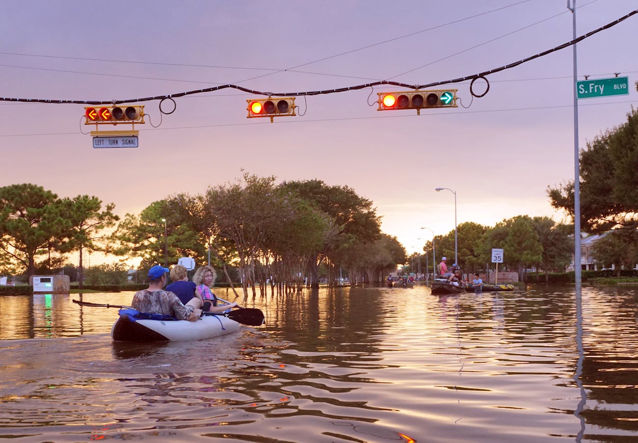 working traffic lights over flooded Houston streets and boats with people at sunset