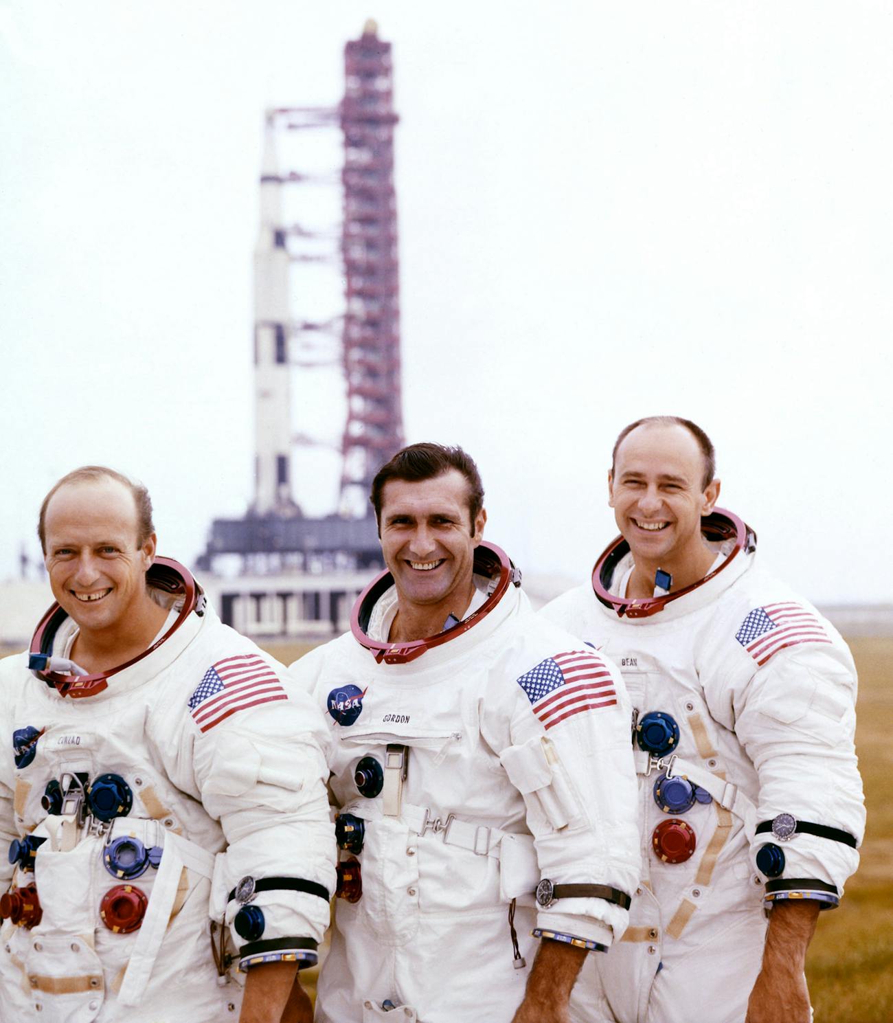 From left to right: Pete Conrad, Dick Gordon, and Alan Bean pose with their Apollo 12 Saturn V moon rocket in the background on the pad at Cape Canaveral on 29 October 1969