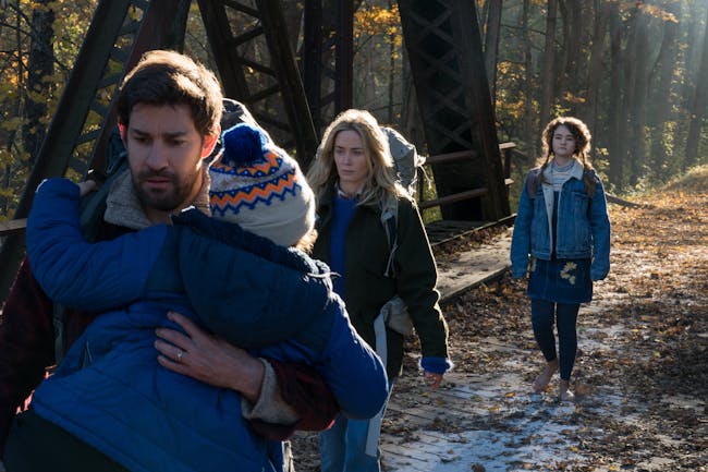 Lee Abbott (John Krasinski) carries his son Marcus (Noah Jupe) with his wife Evelyn (Emily Blunt) and daughter Regan Abbott (Millicent Simmonds) in the background.