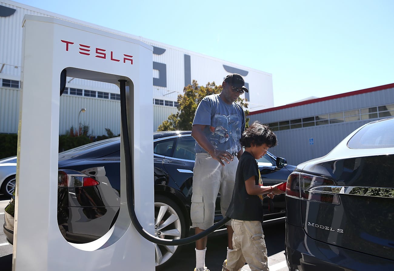 FREMONT, CA - AUGUST 16: Jinyao Desandies (R) and Dandre Desandies (L) plug the Tesla Supercharger into their Tesla Model S sedan outside of the Tesla Factory on August 16, 2013 in Fremont, California. Tesla Motors opened a new Supercharger station with four stalls for public use at their factory in Fremont, California. The Superchargers allow owners of the Tesla Model S to charge their vehicles in 20 to 30 minutes for free. There are now 18 charging stations in the U.S. with plans to open more in the near future. (Photo by Justin Sullivan/Getty Images)