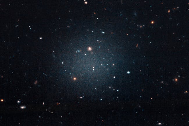 This large, fuzzy-looking galaxy is so diffuse that astronomers call it a “see-through” galaxy because they can clearly see distant galaxies behind it. The ghostly object, catalogued as NGC 1052-DF2, doesn’t have a noticeable central region, or even spiral arms and a disk, typical features of a spiral galaxy. But it doesn’t look like an elliptical galaxy, either. Even its globular clusters are oddballs: they are twice as large as typical stellar groupings seen in other galaxies. All of these oddities pale in comparison to the weirdest aspect of this galaxy: NGC 1052-DF2 is missing most, if not all, of its dark matter.